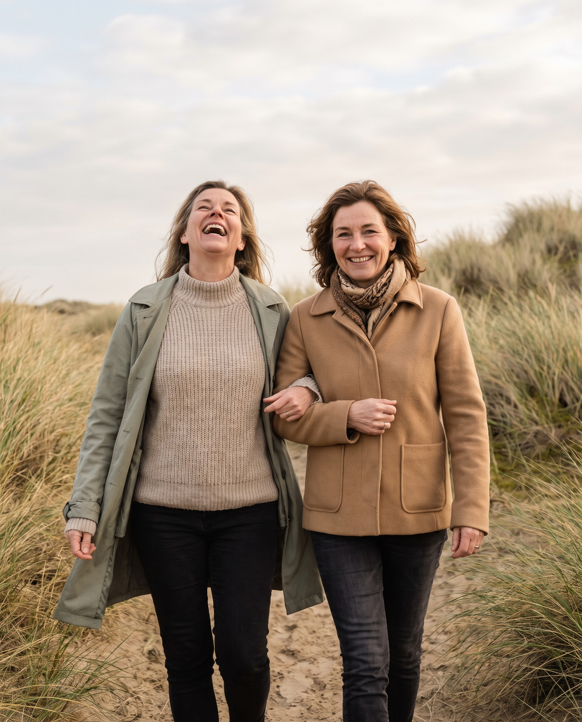 Two women in their fifties walking on a dune path by the sea